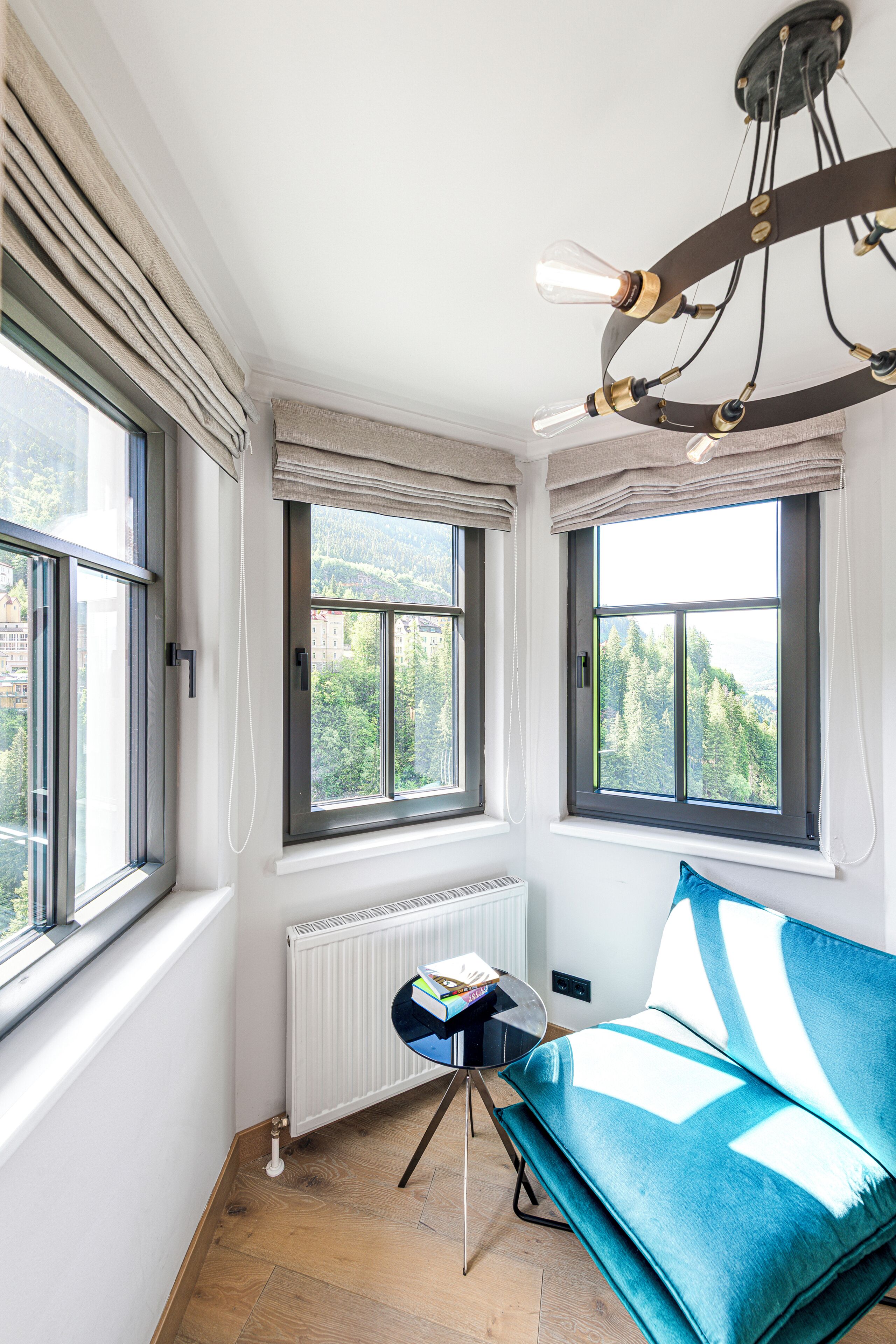 Een kamer met een blauwe bank, een tafel met boeken en een radiator.