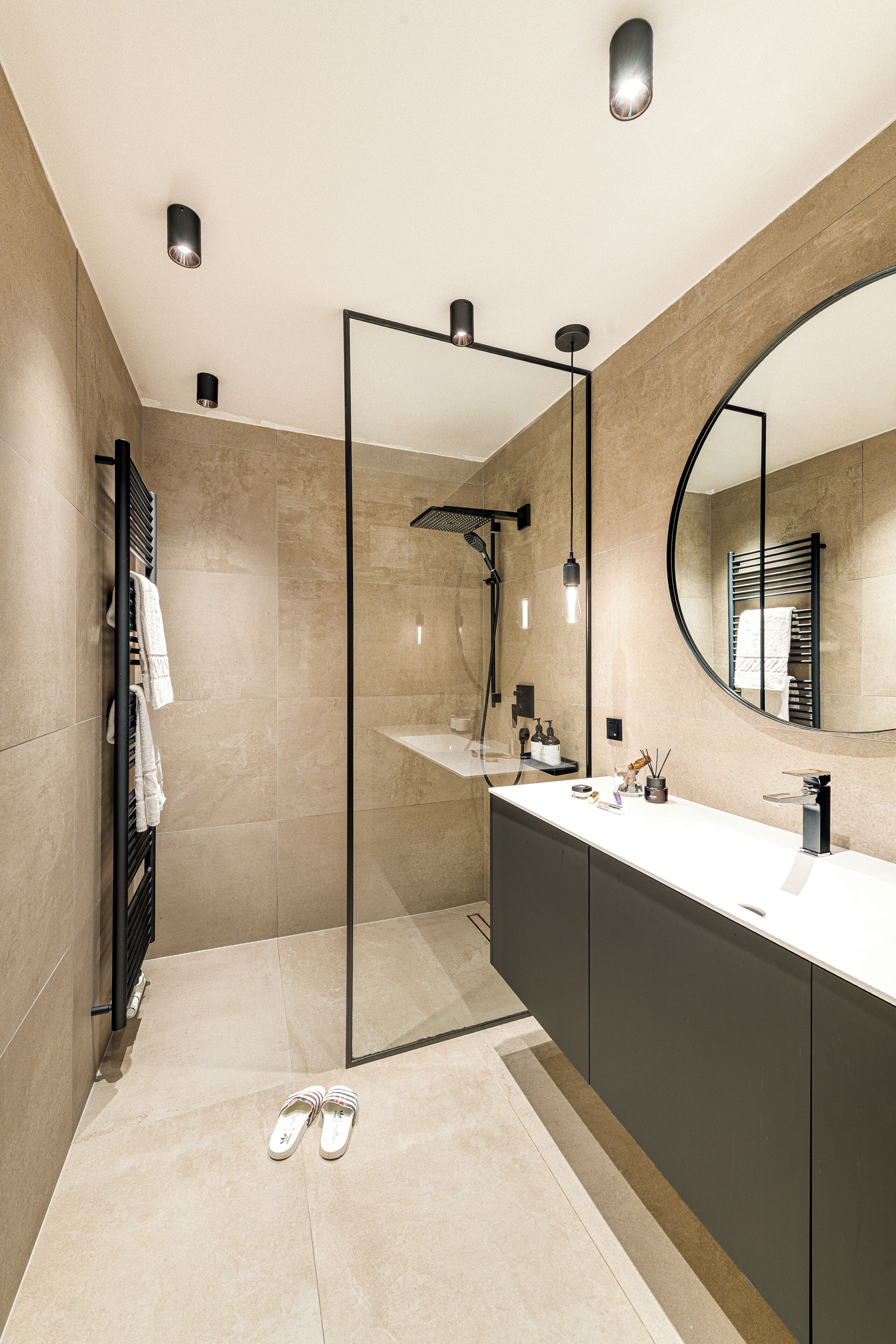 A modern bathroom with a large mirror, a shower area, and a vanity with a sink.