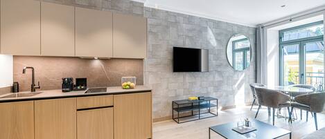Una cocina moderna con armarios de madera, horno empotrado y televisor de pantalla plana en la pared.
