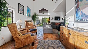 A spacious living area with wicker furniture, a grey sofa, and a wooden cabinet. - Tennis Villa #18, 2 Bedrooms,  2.5 Baths Tennis Villa, Permit 063439 (La Quinta)