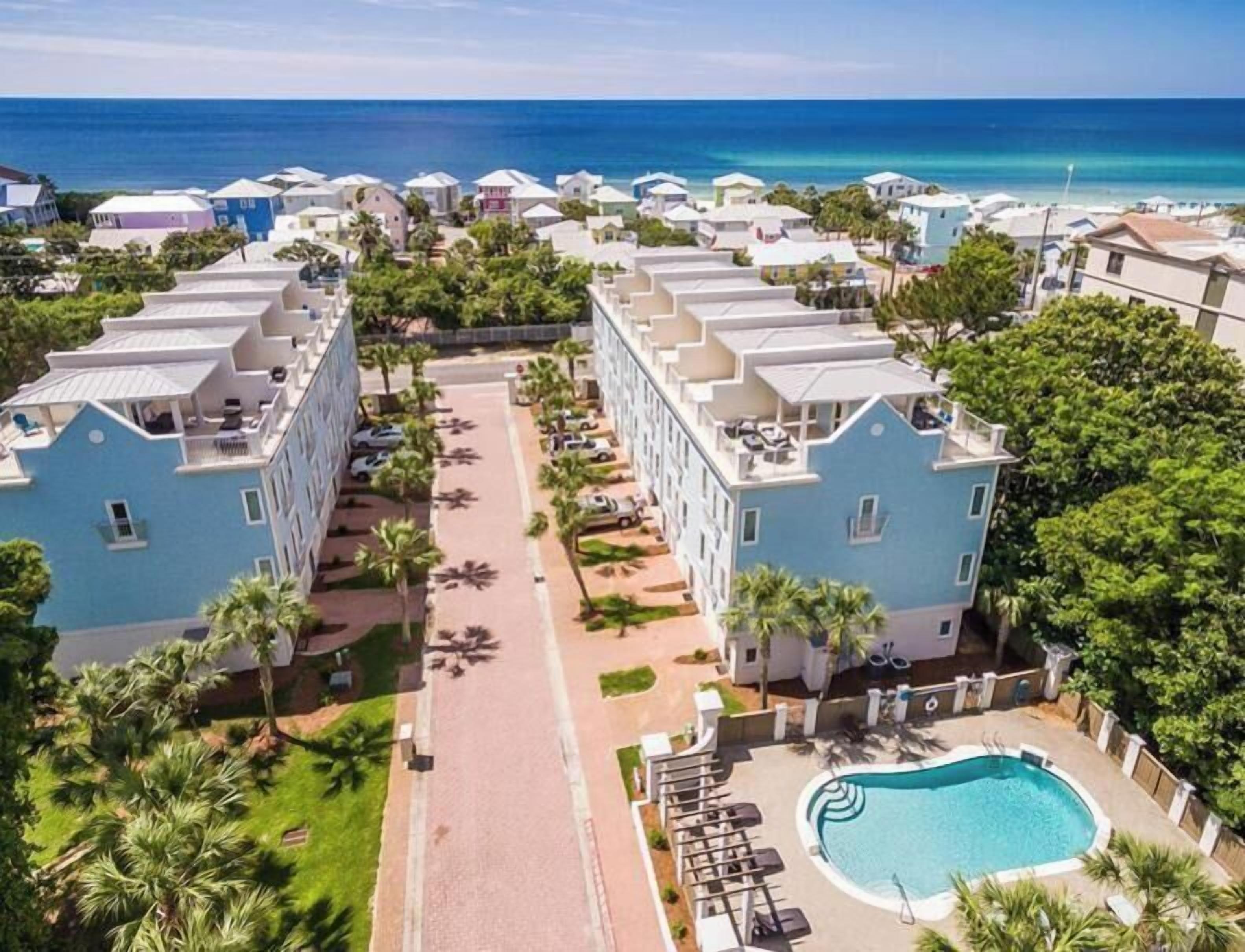 Een resort met meerlaags gebouwen, een centraal gelegen zwembad en uitzicht op de oceaan.