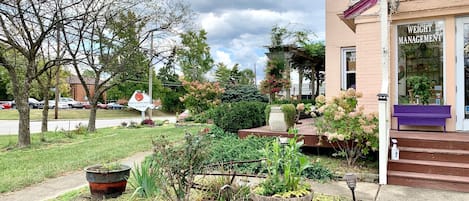 A building with a sign reading "WEIGHT MANAGEMENT" and a garden area with potted plants and a wooden bench.