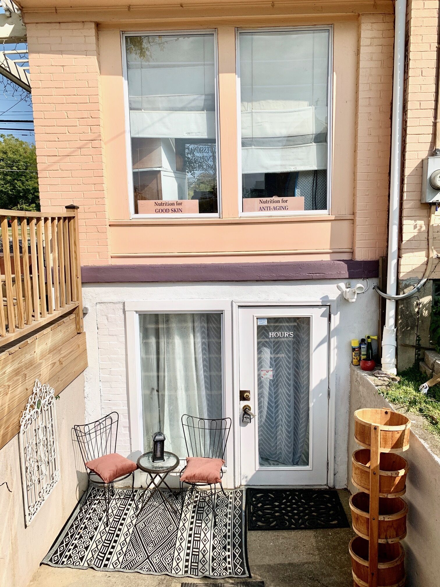 A small patio with a table and chairs, a wooden fence, and a door labeled 'HOURS'.