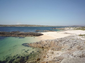 A coastal landscape with clear waters, rocky terrain, and a sandy beach. - Cnocan Na Cuaigh Carraroe (Carraroe)