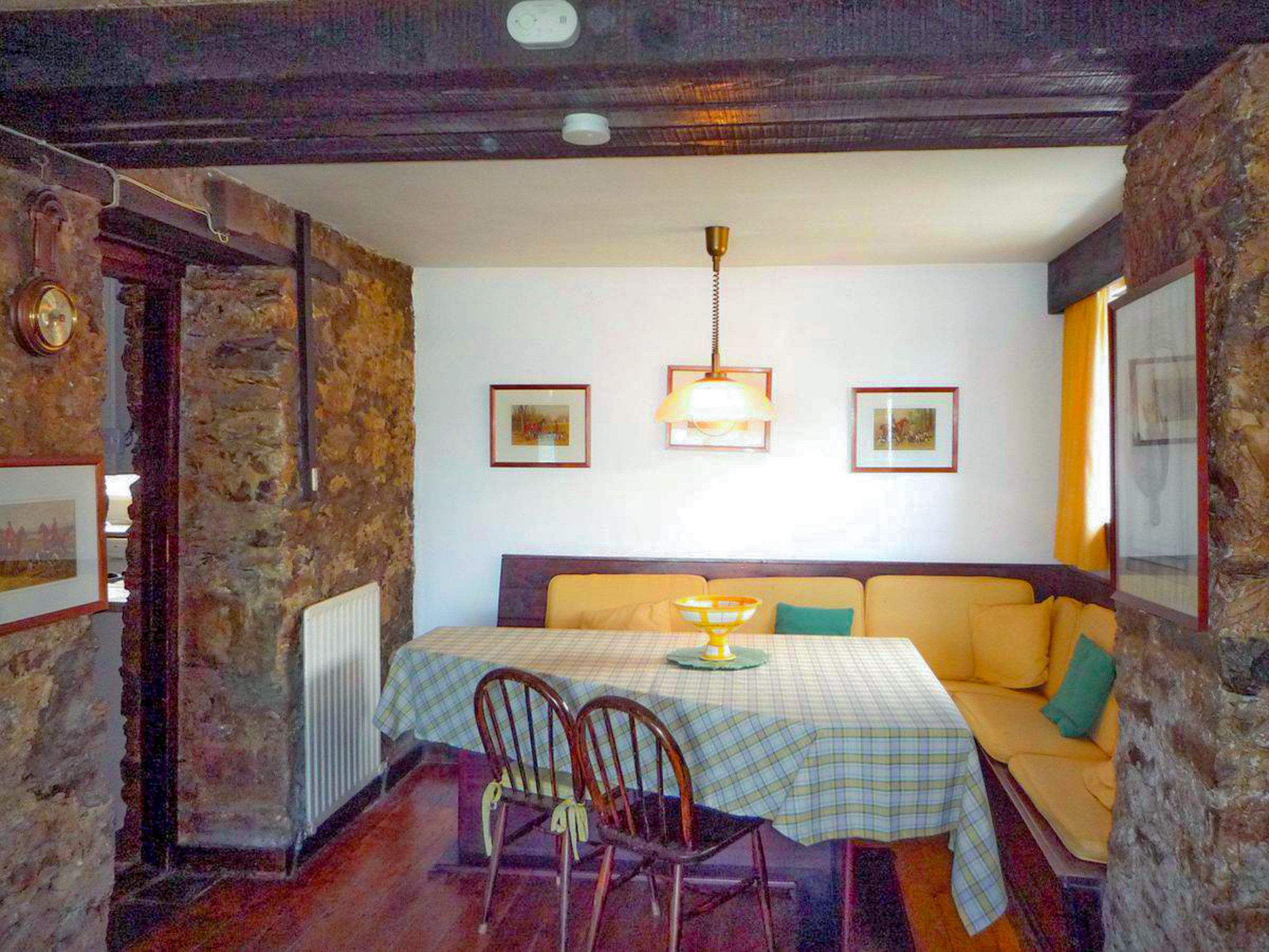 A dining area with a table set for two, a sofa, and a chandelier.