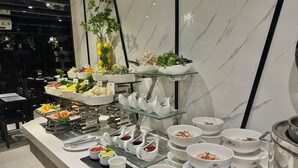 Un bufé con diversos platos y salsas dispuestas en estantes de vidrio.