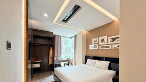 Una habitación de hotel moderna con una cama grande, un escritorio, un armario y una ventana con cortinas.