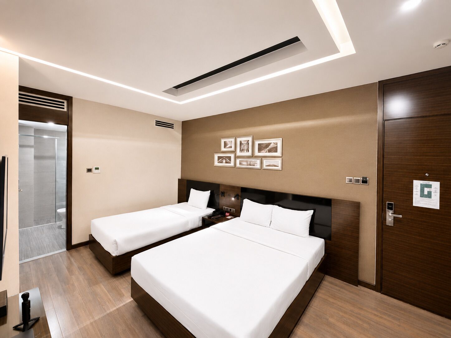 Ein Hotelzimmer mit zwei Betten, einer Dusche und einem Holzschrank.