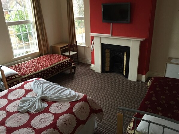 Una habitación de hotel con dos camas, chimenea, televisión y ventanas amplias.