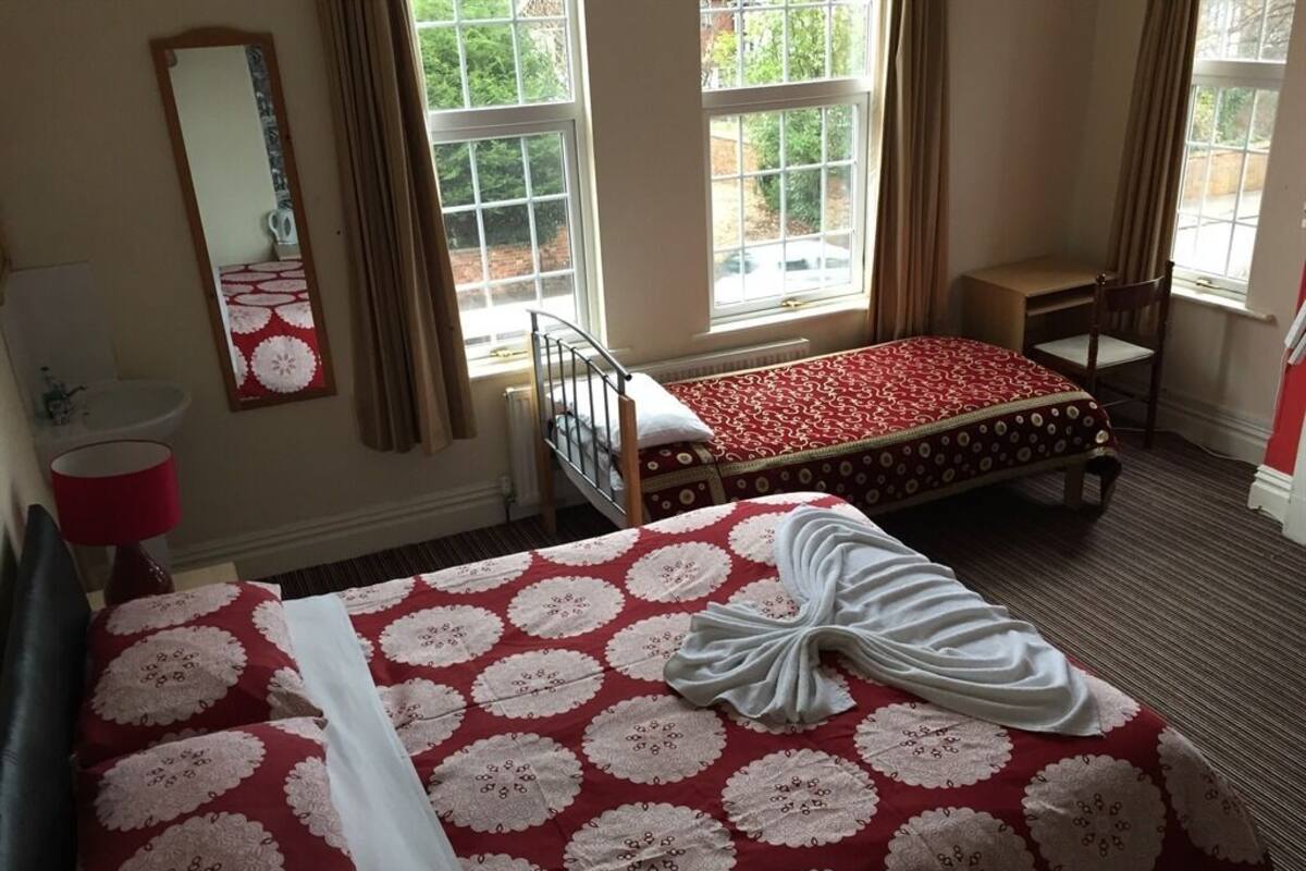 A hotel room with two beds, a sitting area, and large windows.