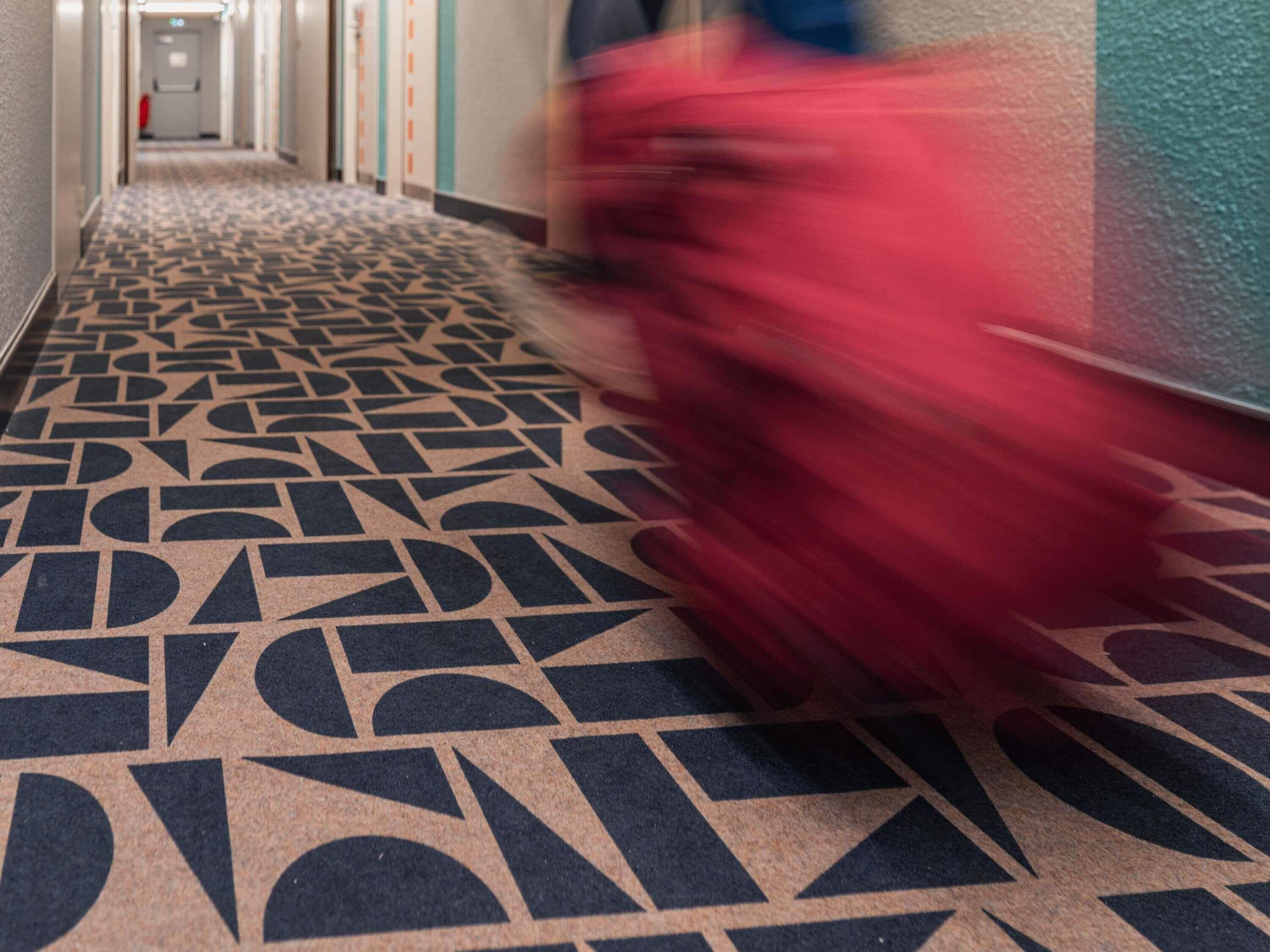 Pasillo con alfombra estampada y barandilla a la derecha.