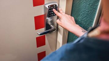 A person using a keypad lock on a door with red and white panels.