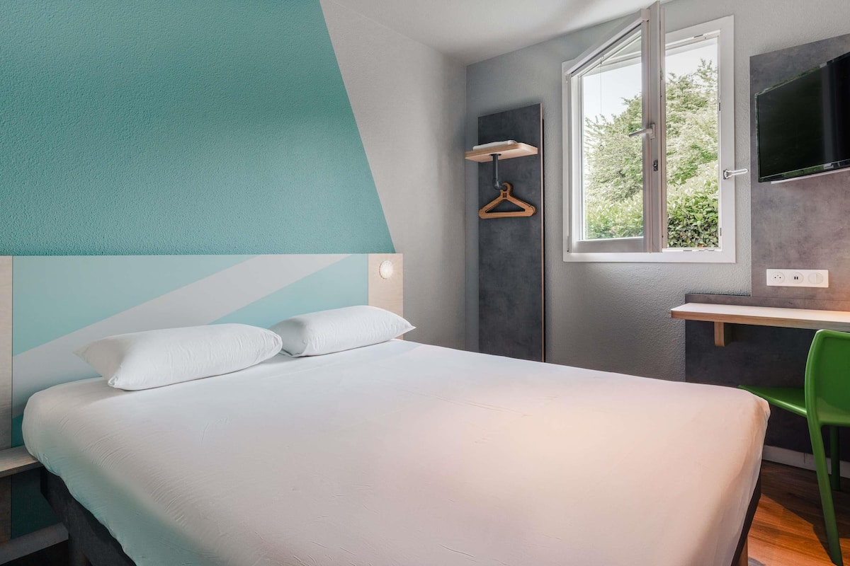 A modern bedroom with a bed, a desk, and a chair.