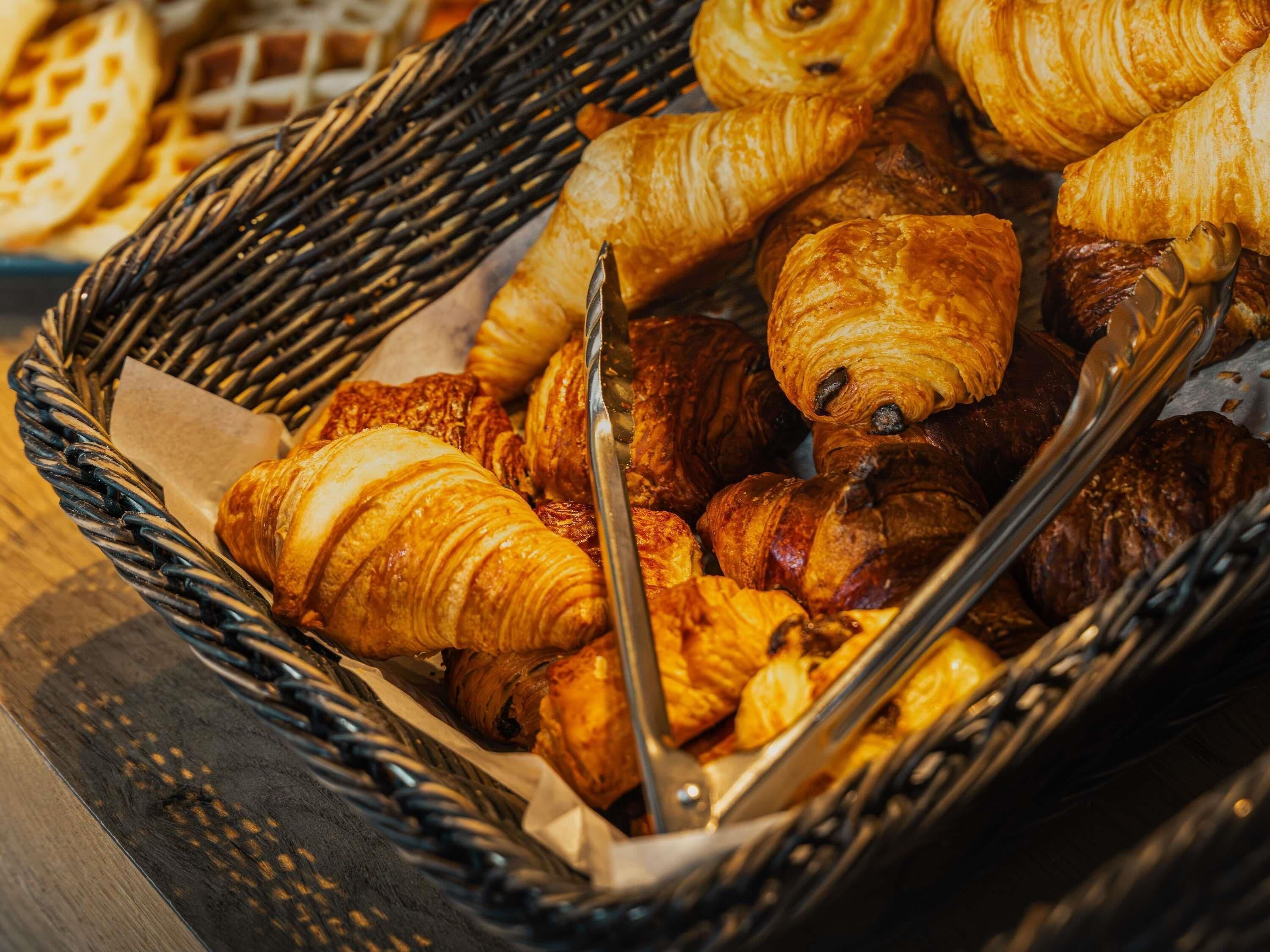 Una cesta rebosante de diversos tipos de pastelería, incluyendo croissants y otras delicias horneadas.