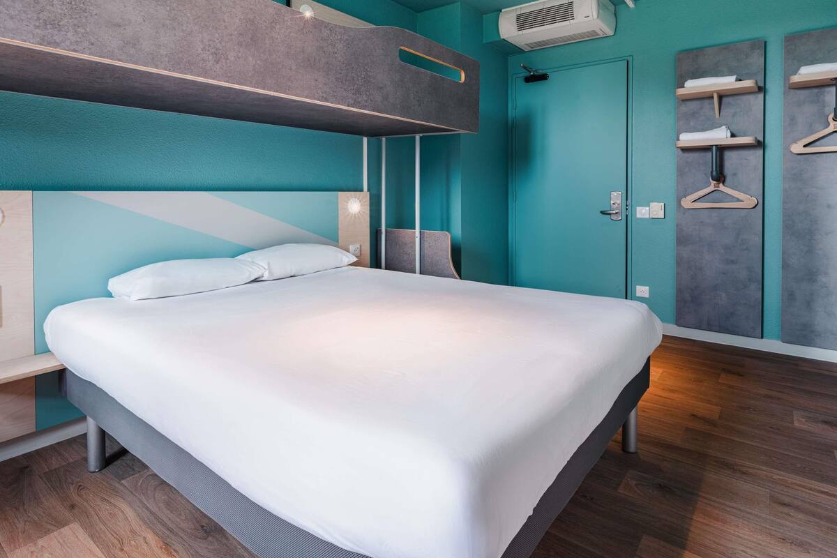 A modern bedroom with a bunk bed, a wardrobe with a mirror, and a ceiling-mounted projector.