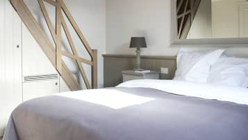 Ein Schlafzimmer mit einem Bett, einem Nachttisch, einer Lampe, einem Spiegel und einer Holztreppe.