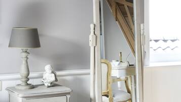 A bedroom with a bed, a dresser, a lamp, a mirror, and a window.