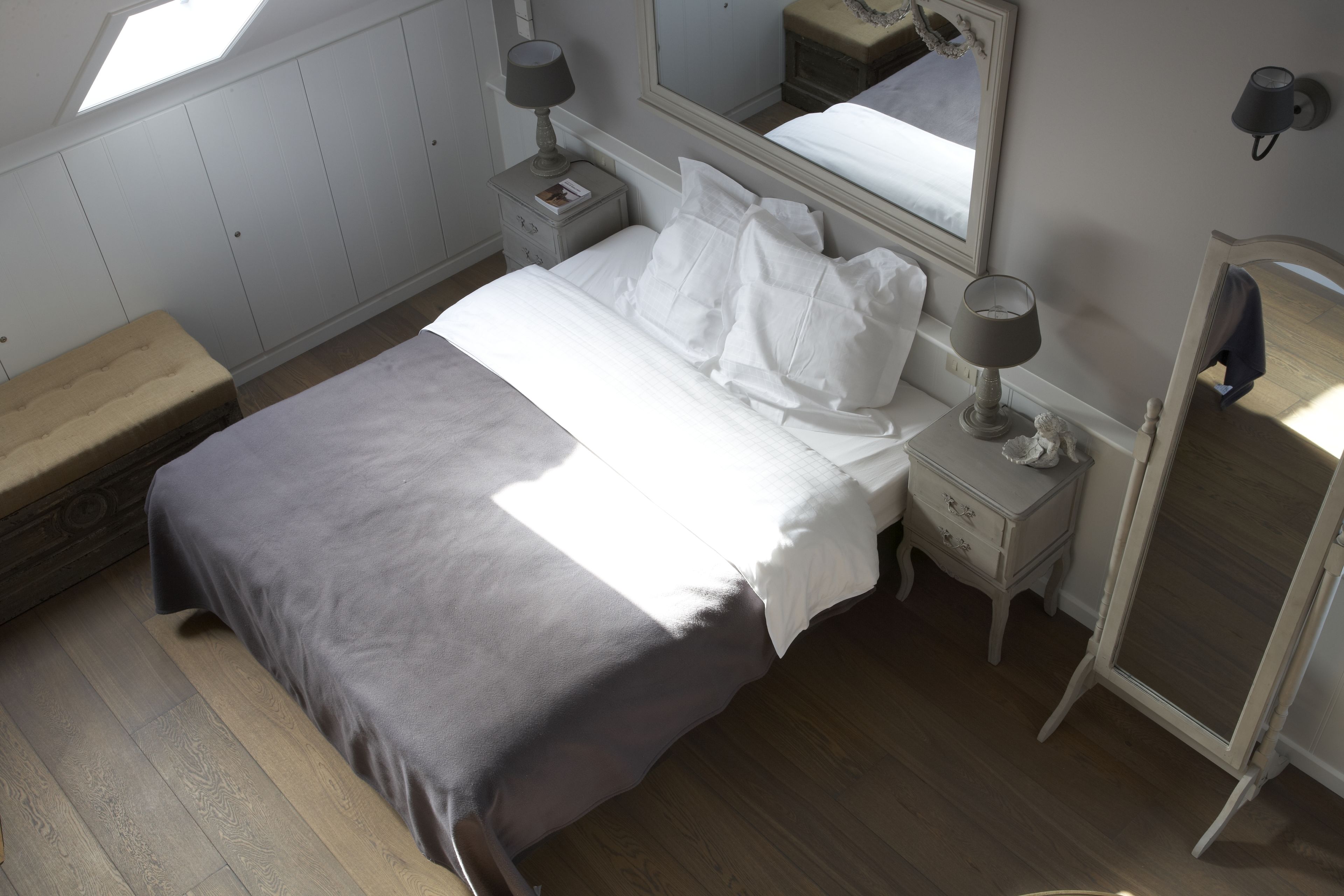 Un dormitorio con cama, mesitas de noche, un espejo y una ventana.