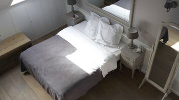 Un dormitorio con cama, mesitas de noche, un espejo y una ventana.