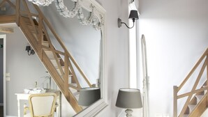 A bedroom with a large mirror, a bed, a nightstand, a lamp, a chair, and a staircase. - B&B Cimbarsaca (Gavere)