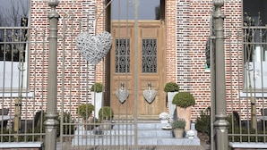A brick building with a wooden door, a circular window above the door, and a small circular skylight on the roof. - B&B Cimbarsaca (Gavere)