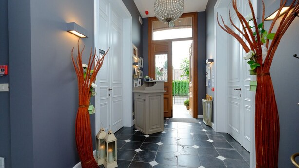 A hallway with a checkered floor, white doors, and a chandelier. - B&B Cimbarsaca (Gavere)