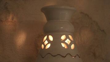 Un candelabro de cerámica blanca con diseños recortados sobre una pared con textura.