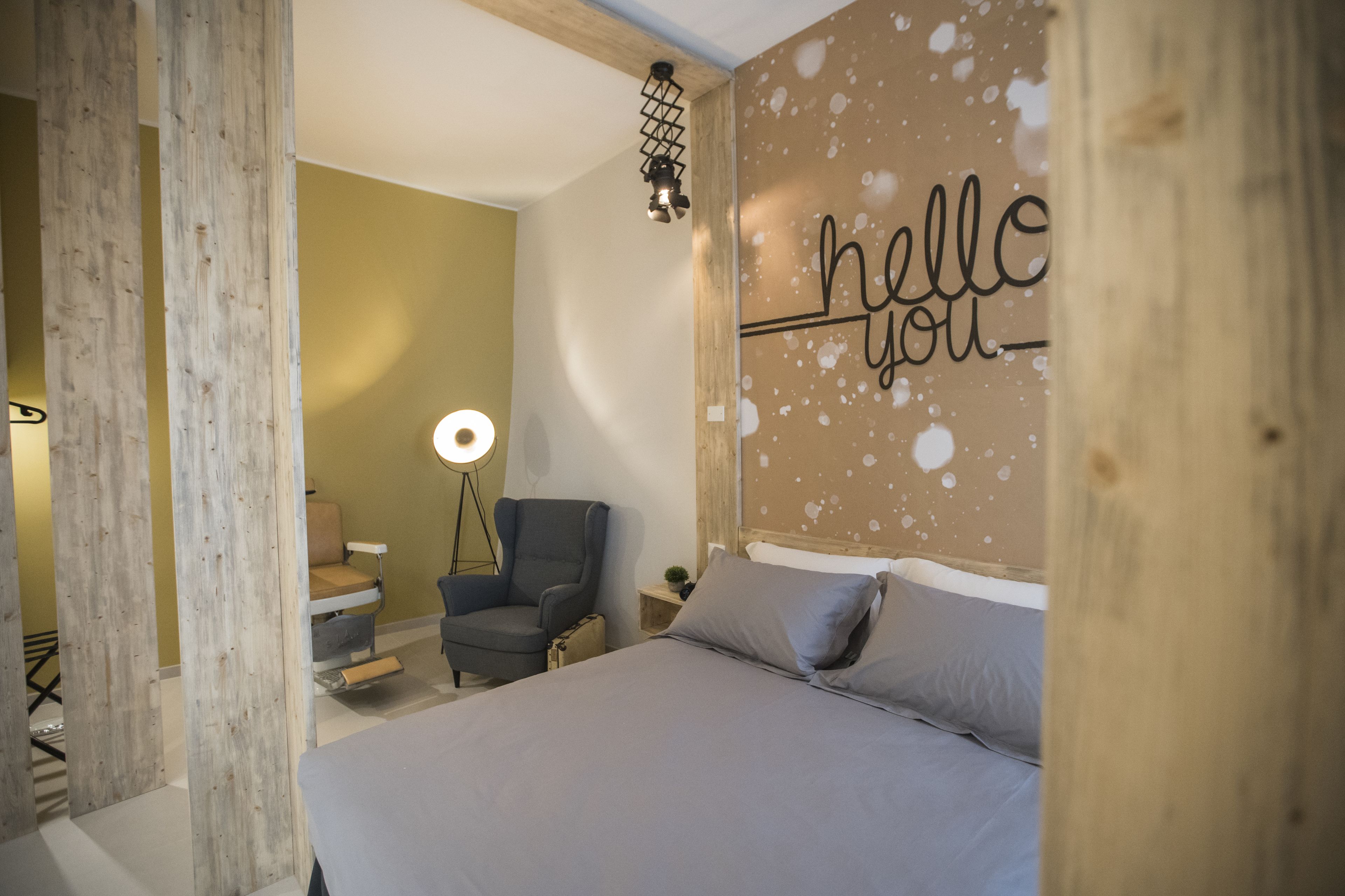 Un dormitorio con cama, una silla, un escritorio, una lámpara y una pared con el texto "hello you".