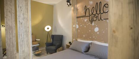 A bedroom with a bed, a chair, a desk, a lamp, and a wall with the text "hello you".