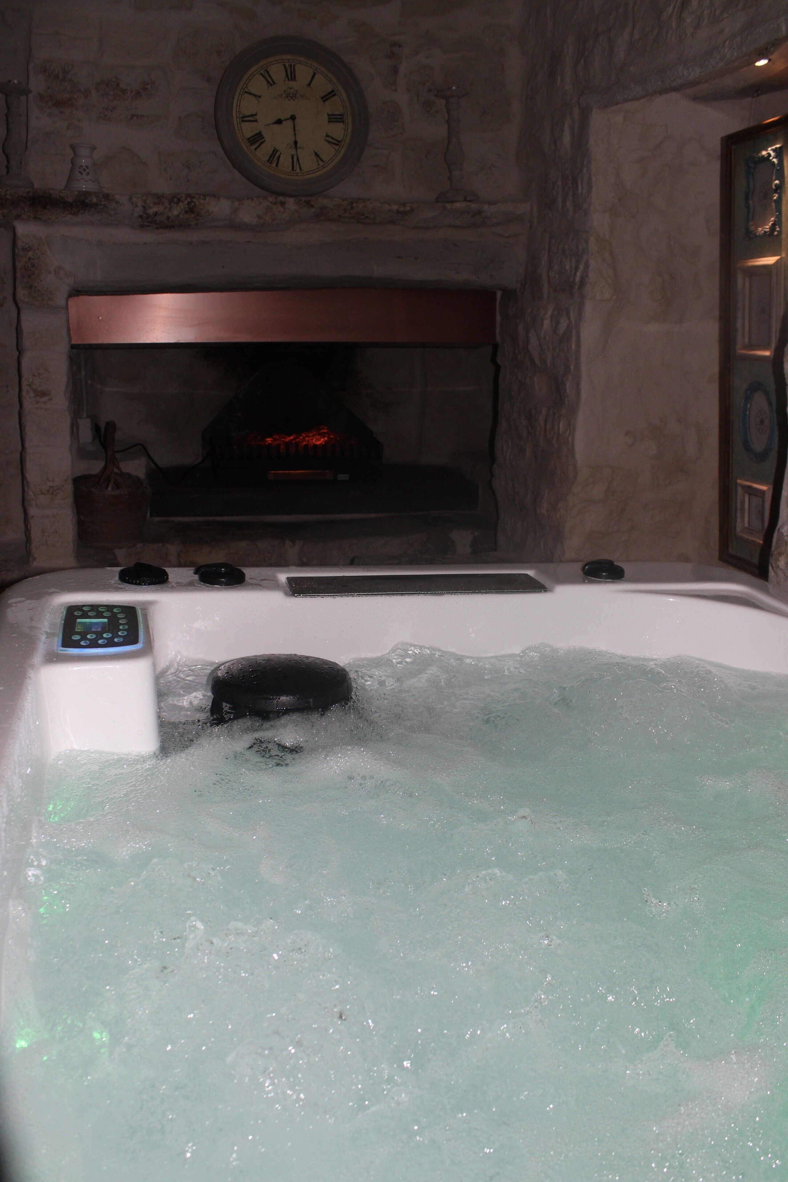 Ein Whirlpool mit Bedienfeld, eine Wanduhr und ein Kamin im Hintergrund.