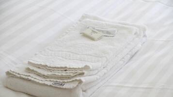 A neatly folded white towel with a label on a bed with striped bedding.