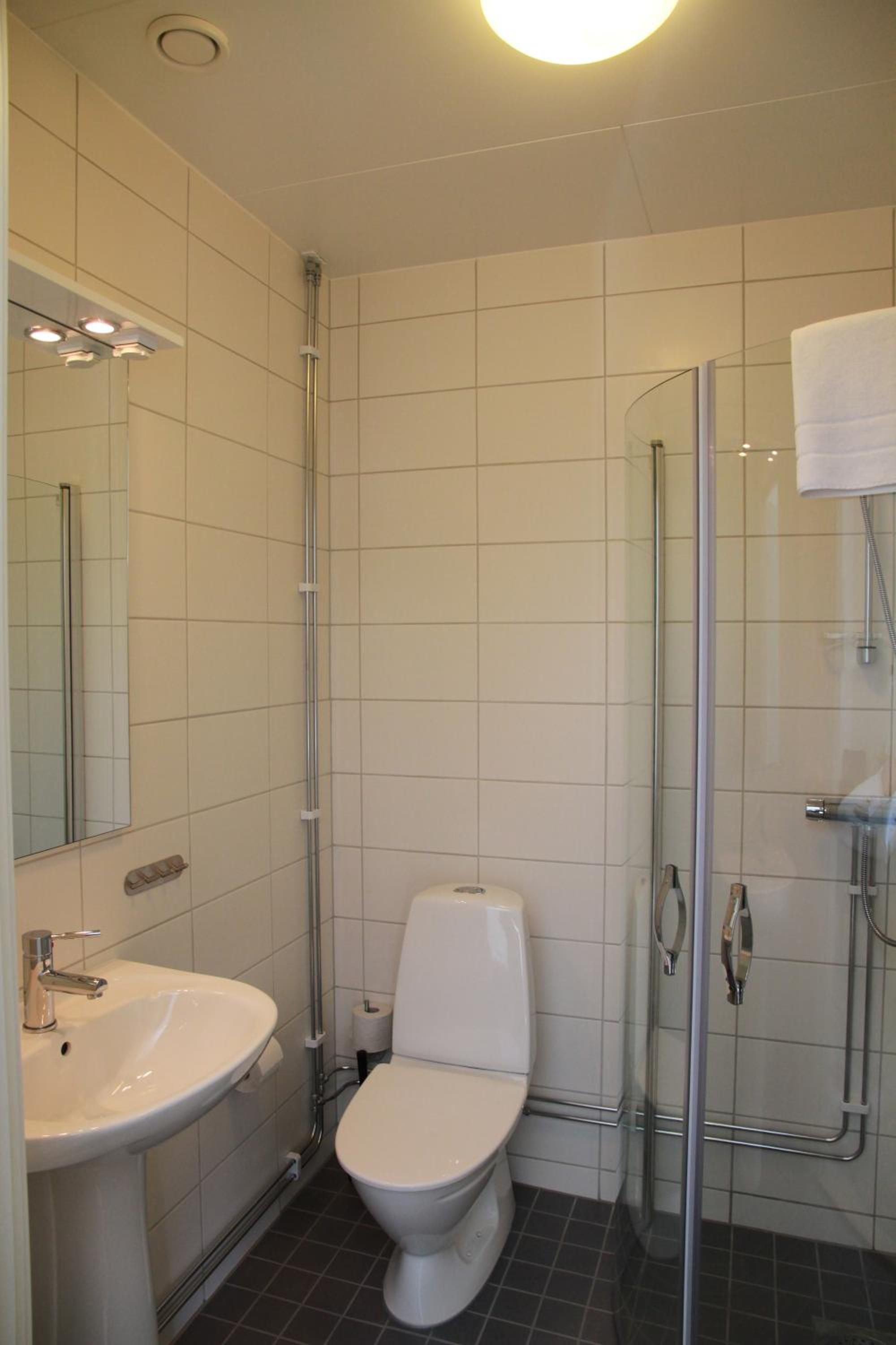Un baño con inodoro, lavamanos y cabina de ducha de vidrio.