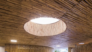 Een receptiehal met een rond zitgedeelte, bamboe wanden en een centraal hanglamp.