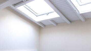 Una stanza con soffitto spiovente e lucernari.