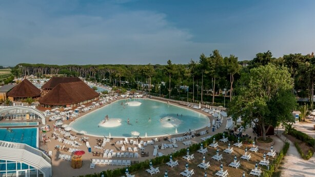 Een resort met een groot centraal zwembad, meerdere kleinere zwembaden en diverse ligbedden en parasols.