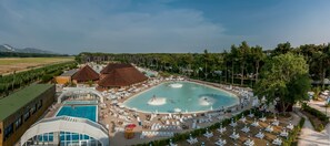 Un complexe hôtelier doté d’une grande piscine centrale, de plusieurs piscines plus petites et d’une variété de chaises longues et de parasols.