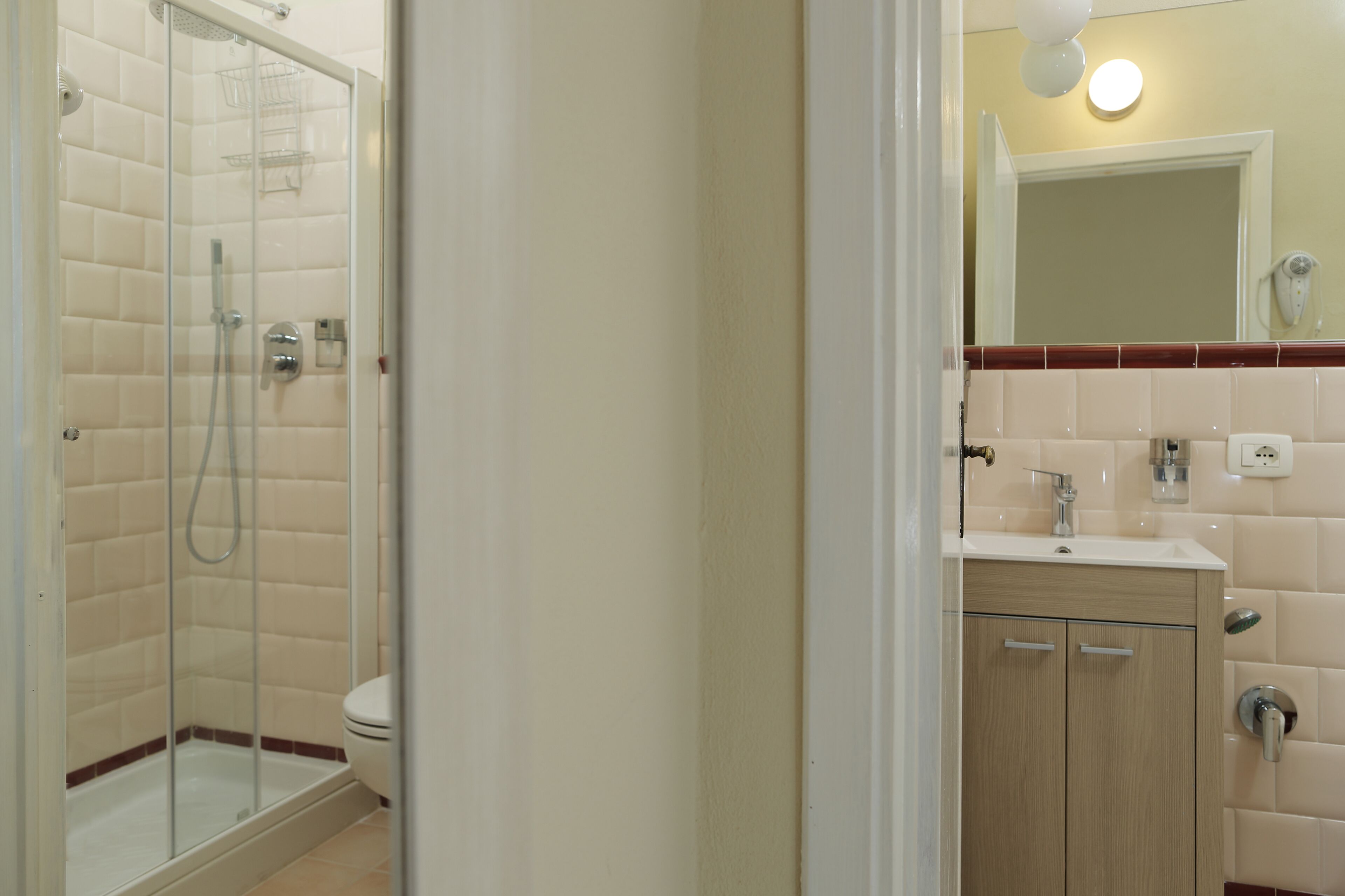 A bathroom with a glass-enclosed shower, a toilet, and a vanity with a mirror.