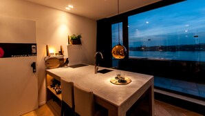 A modern kitchen with a large window, a pendant light, and a view of the cityscape. - Kaai 11 (Antwerp)