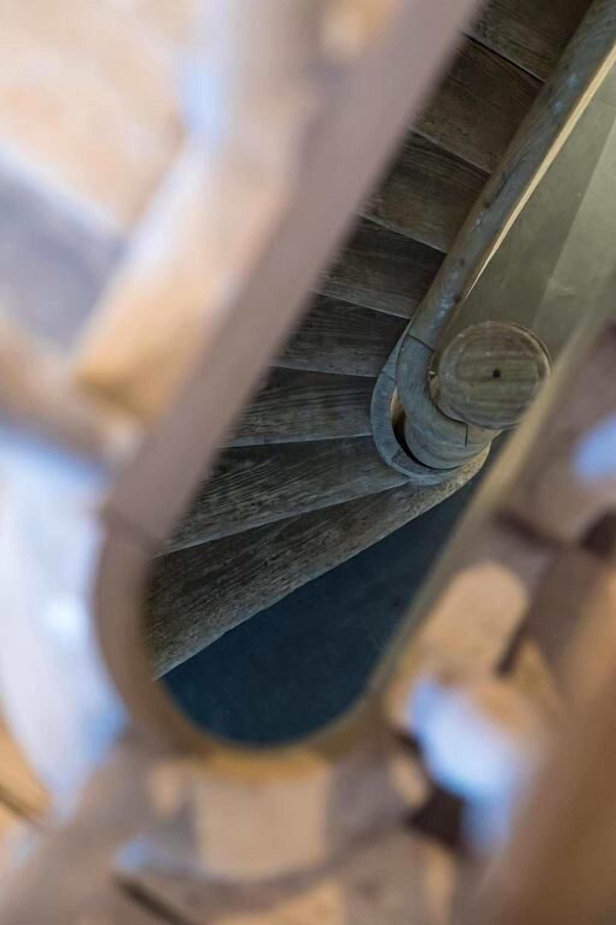 Gros plan d’un escalier en colimaçon avec une main courante en bois et une balustrade en métal.