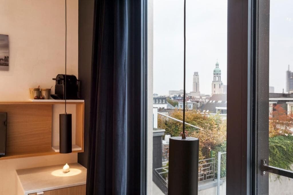 Een modern interieur met uitzicht op de stad, met een houten plank, een hanglamp en een kaars op een tafel.