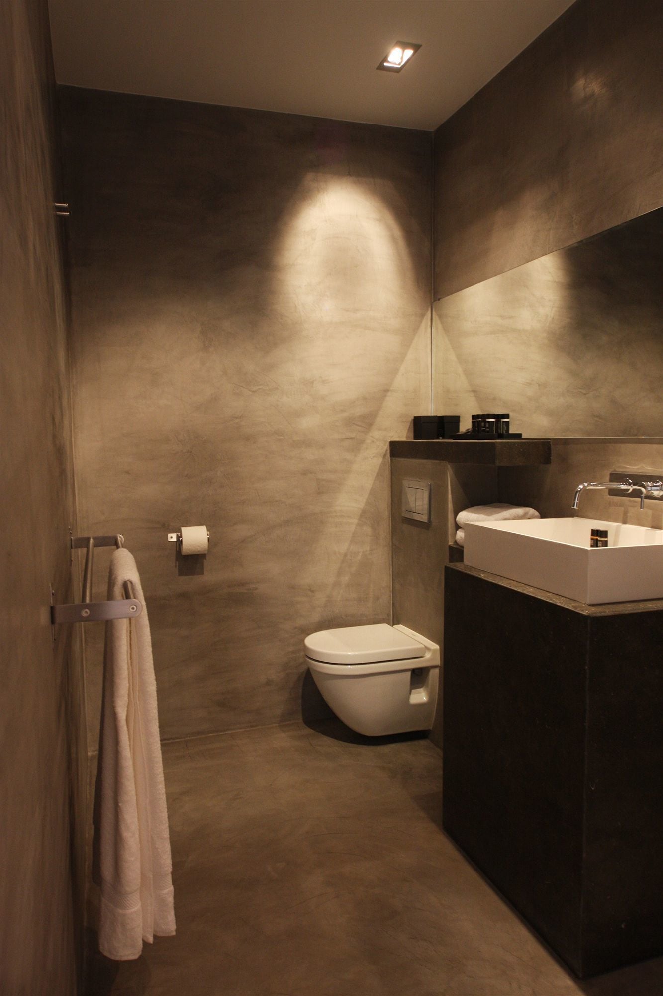 Une salle de bain moderne avec un grand miroir, un lavabo blanc et des toilettes.