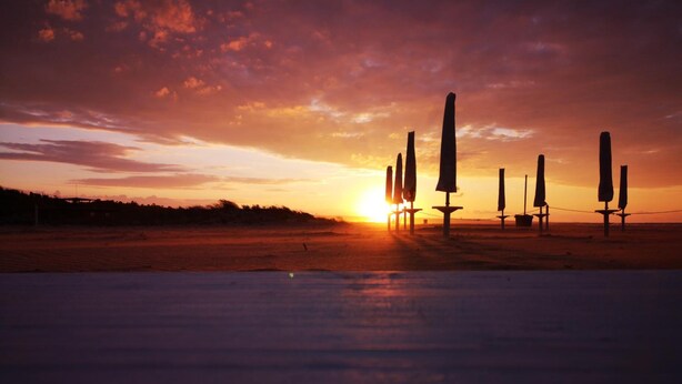 A beach with windsurfers silhouetted against a sunset. - Hotel Di Nardo (Petacciato)