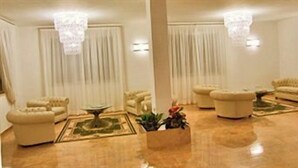 A spacious living room with a large chandelier, a sofa set, and a coffee table. - Hotel Di Nardo (Petacciato)