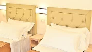 Two twin beds with headboards, each with a bedside table and lamp.