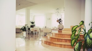 A modern interior with a wooden staircase, a dining area with chairs, and potted plants. - Hotel Di Nardo (Petacciato)