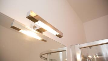 Un baño moderno con cabina de ducha de vidrio y un aplique en el techo.
