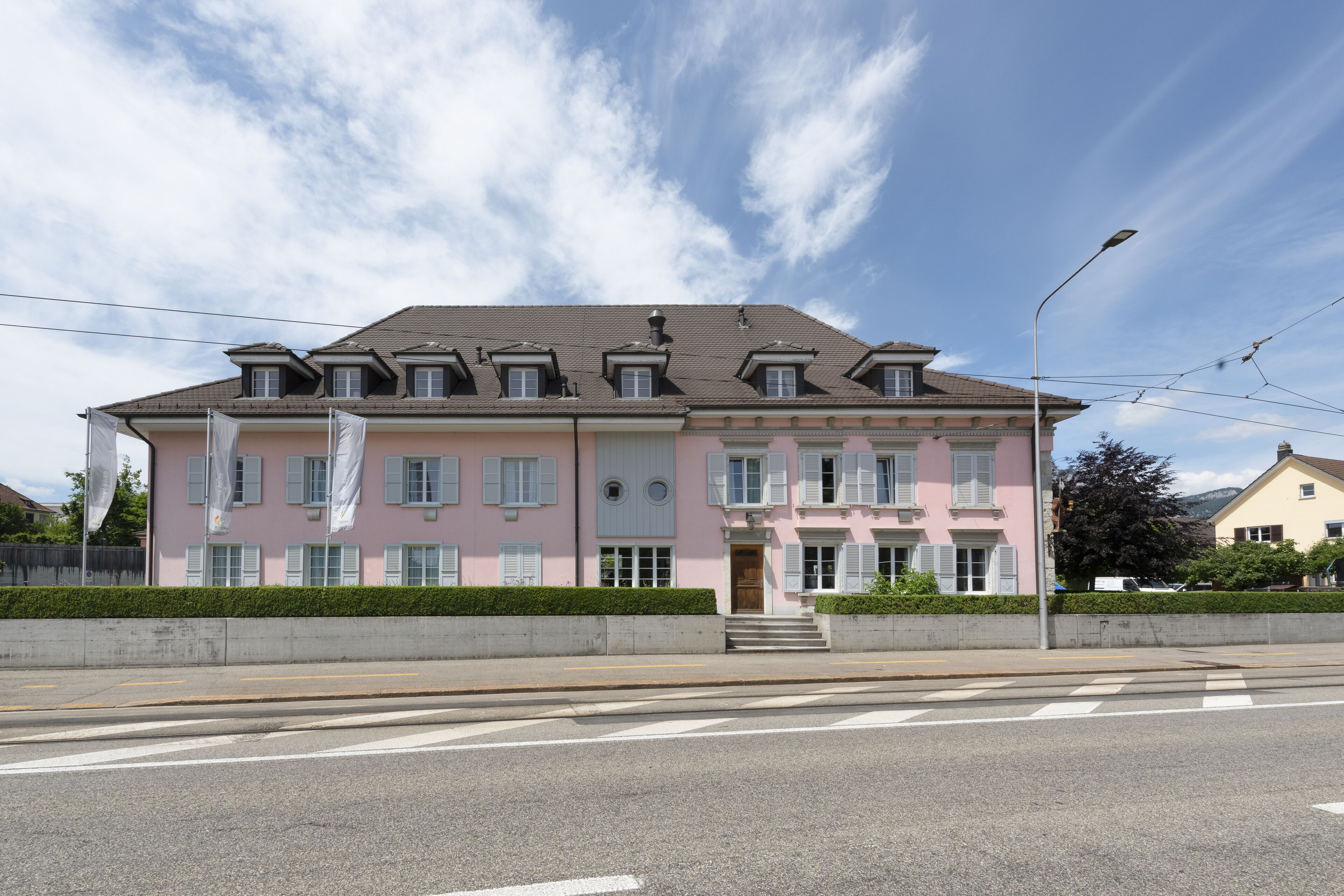 A pink building with multiple windows and a central entrance.