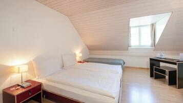 Ein Schlafzimmer mit einem Bett, Nachttischen, einem Schreibtisch und einem Fenster.