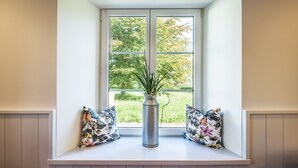 Un siège de fenêtre agrémenté d’une plante en pot et de deux coussins décoratifs.