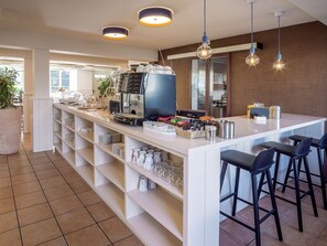 A modern kitchen with a coffee machine, bar stools, and shelves with kitchenware.